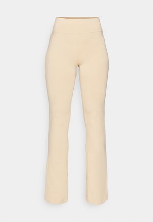 Beige flared leggings met een hoge tailleband, gemaakt van zachte, rekbare stof. Glad textuur, geen zichtbare patronen of hardware details.