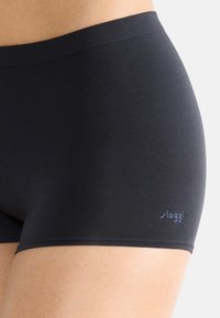 Svarta boxertrosor i bomullsblandning med en slät textur och en subtil logotyp på vänster höft. Har en mjuk midja och inga synliga sömmar.