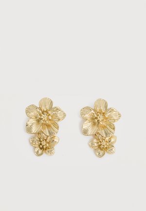 Boucles d'oreilles dorées présentant deux fleurs texturées superposées avec des pétales détaillés et des accents de perles centrales.