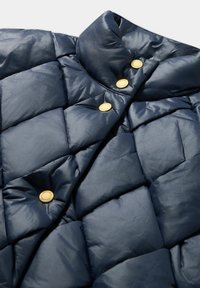 Granatowa pikowana kurtka puchowa z wysokim kołnierzem i trzema złotymi zatrzaskami. Gładki, błyszczący materiał z pikowaniem w kształcie diamentów.