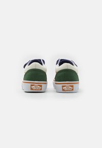 Zapatillas verdes y blancas con acentos azules, materiales de ante y cuero, que presentan una suela de goma blanca y el logo naranja de Vans en el talón.