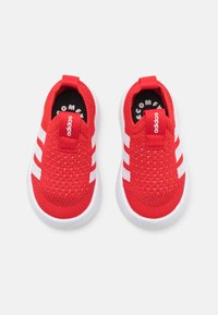 Rote gestrickte Slip-On-Sneaker mit weißen drei Streifen, Gummisohlen und einem weichen, strukturierten Obermaterial, das ein Logo an der Ferse aufweist.