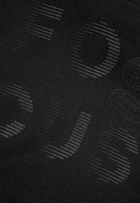 Czarna bluza z teksturowanym, tonalnym grafiką z napisem „FOCUS” w różnej grubości linii, z abstrakcyjnym wzorem globu. Miękki materiał.