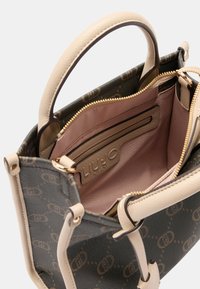 Bruine en beige totebag met een getextureerde buitenkant, gouden rits en een zachtroze binnenkant. Inclusief een zakje met rits en merkdetail.