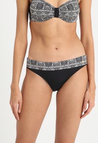 Čierne bikini nohavičky s vzorovaným pásom. Dizajn obsahuje kvetinový motív v čiernej a bielej farbe na elastickej textúre pre pohodlie.