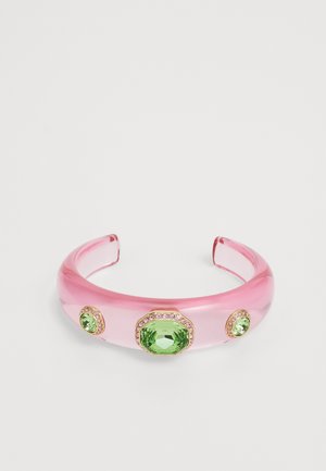 Un serre-tête en acrylique transparent rose avec des embellissements en pierres vertes. Il présente deux petites pierres et une plus grande encadrées de accents dorés.