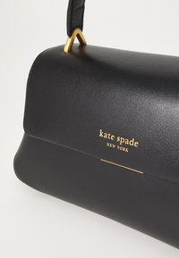 Borsa a mano in pelle nera con un design strutturato, dotata di un accento in metallo dorato e logo impresso sul davanti. Texture liscia.