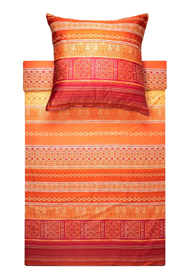 Set di biancheria da letto con vivaci strisce arancioni e rosse, caratterizzato da motivi e trame intricate su cuscini e copriletto. Materiale in cotone.
