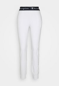 Białe sportowe spodnie z czarnym elastycznym paskiem w talii, na którym znajduje się logo "Champion". Gładka tkanina, dopasowany krój, zwężane mankiety.