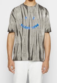 Tričko s krátkým rukávem v šedém tie-dye s modrým textem "PAUL SMITH" a dvěma tečkami nad ním, vyrobené z měkké bavlněné směsi.