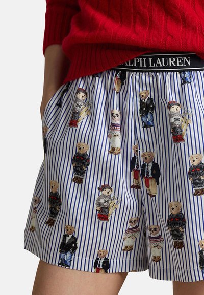 Randiga shorts med tryckta teddybjörnar klädda i olika outfits och ett svart midjeband märkt "Ralph Lauren", kombinerade med en röd tröja.