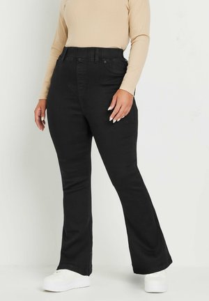Zwarte flared jeans met een hoge taille, gemaakt van denim. Beschikt over een klassiek vijf-pocket ontwerp en subtiele stiksels. Gecombineerd met witte sneakers.