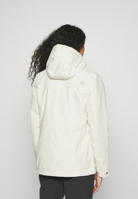 Chaqueta impermeable blanca con capucha, que presenta un logo sutil en la espalda, textura suave y bolsillos laterales con detalles de botones.