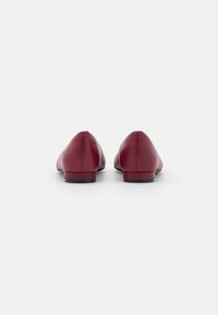 Ballerines en cuir bordeaux avec un design à bout pointu et un talon minimal. Texture lisse avec des coutures sans couture et un profil épuré et élancé.