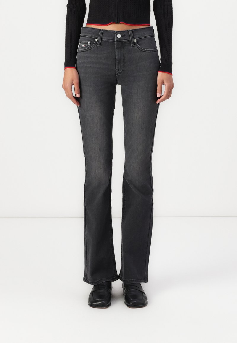 Dark grey flared jeans with a smooth texture, five-pocket design, and subtle stitching. Features a metal button and zipper fly closure.