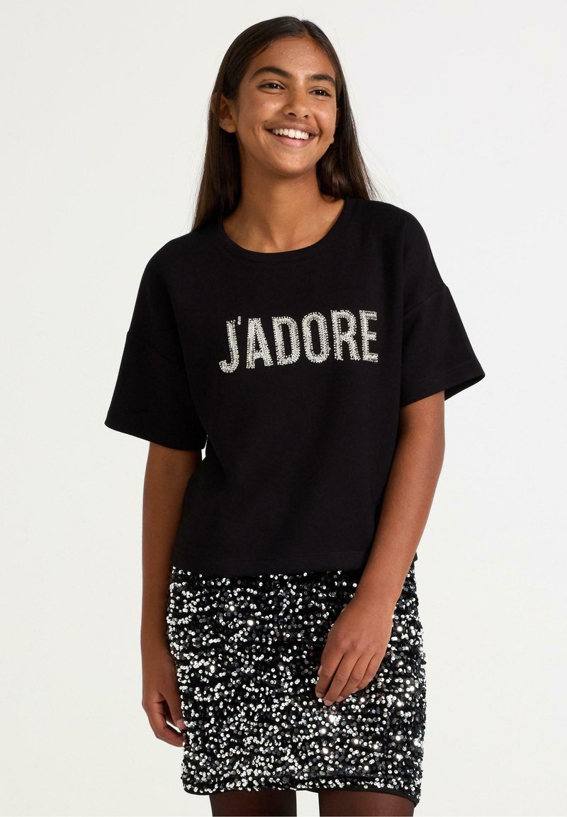 Sort kortærmet t-shirt med glitrende "J'adore" tekst, kombineret med en sort mini-nederdel med palietter. Glatte teksturer med blanke accenter.
