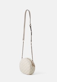 Rund cremet tekstureret crossbody taske med guld lynlås og sort-guld kædetrækkombineret med justerbar beige læderrem.
