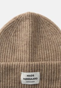 Gorro de malha beige com textura canelada e dobra na bainha. A etiqueta lê "MADS NØRGAARD COPENHAGEN." Material de lã macia.