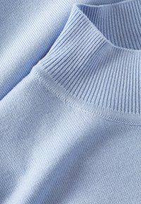 Light blue knitted sweater with a ribbed high collar. Soft texture, featuring a smooth body and detailed stitching along the edges.