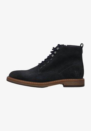 Bottes en daim noir à chevilles avec un bout rond, un laçage, une semelle contrastante marron et un accent de logo sur le talon.