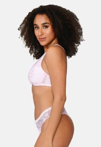 Bra in pizzo rosa chiaro con ricami floreali e pannelli trasparenti, abbinato a culotte semi-trasparenti con dettagli intricati.