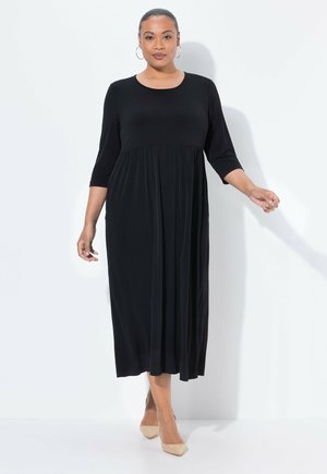 Musta, polvipituinen mekko, jossa on pyöreä kaula-aukko, kolme neljäsosaa hihat ja kokoontunut vyötärö, valmistettu pehmeästä, valuvaista kankaasta.