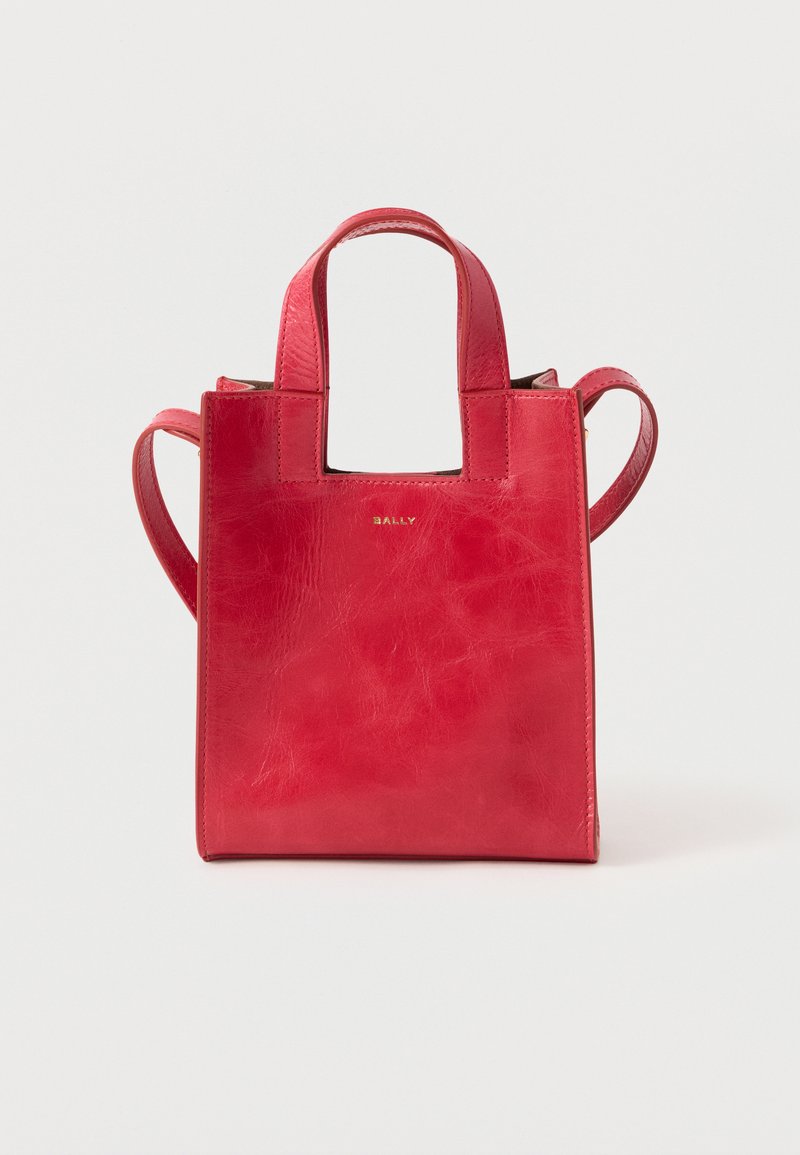 Sac cabas en cuir rouge avec des poignées courtes et une bandoulière, avec le logo "BALLY" doré au centre avant.