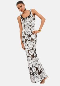 Rochie de seară din dantelă neagră cu model floral alb, siluetă ajustată, decolteu cu margini ondulate și bretele pe umeri. Accentuata cu un tiv negru.