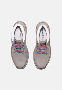 Scarpe di pelle grigia con bordi bianchi, lacci multicolori in rosa e blu, suole piatte e un logo visibile sulla linguetta.