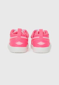 Pink athletic shoes with a synthetic upper, mesh accents, and a white rubber sole. Features a Velcro strap and logo on the heel.