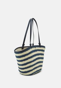 Woven tote bag featuring navy and cream stripes, made from a flexible material with two long leather handles and an open top.