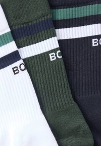 Kolm paari kootud sokke: valged tumesiniste ja rohelist triipudega, tumerohelised tumesinise triibuga ning tumehallid rohelise triibuga. Pehme tekstuur.