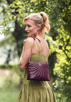 Burgundská syntetická kabelka s prošívaným vírovým designem a zlatými prvky, obsahující řetízkový popruh a boční detail s třásněmi.