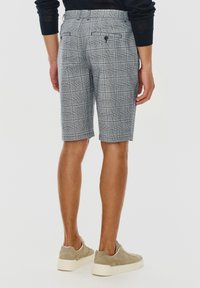 Szare szorty w kratę o slim fit, z dwoma tylnymi kieszeniami, z zapięciem na guziki i dopasowanym wyglądem. Stylizowane z beżowymi trampkami.