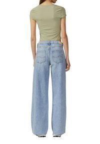 Olivi vihreä ribattu lyhythihainen cropped-paita yhdistettynä vaaleansinisiin leveälahkeisiin farkkuihin, joissa on takataskut ja istuva vyötärö.