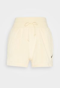 Krémově zbarvené plyšové froté šortky s elastickým pasem, nastavitelným stahovacím šňůrkem a malým černým logem Nike na levé straně.