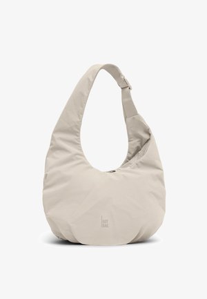 Beżowa torba na ramię w kształcie półksiężyca z szerokim paskiem i subtelnym logo "GOT BAG." na środku z przodu.