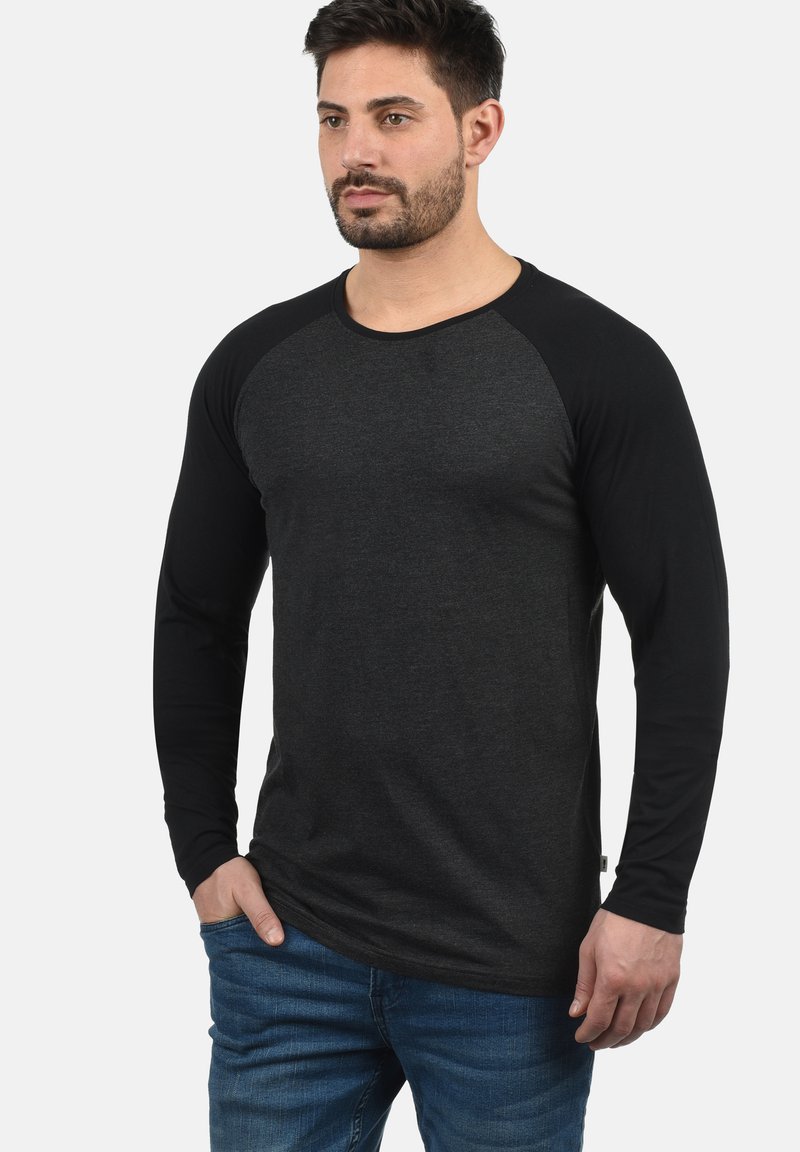 Schwarzes Langarm-T-Shirt mit einem dunkelgrauen Körper, kontrastierenden schwarzen Raglanärmeln, aus weichem Stoff. Hat einen Rundhalsausschnitt und eine lockere Passform.