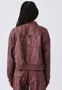 Bordeaux, cropped jack met ribgebreide cuffs en onderrand, gemaakt van textuurstof. Bevat een rechthoekig label op de bovenrug.