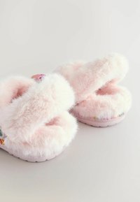 Flauschige rosa Hausschuhe mit Kreuzriemen, weicher Textur, mit einem gemusterten Sohlen und bunten Akzenten entlang des Randes der Außensohle.
