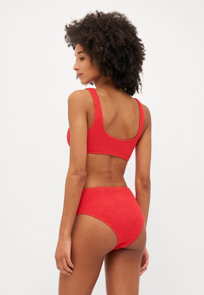 Rød teksturert bikini-sett som inkluderer en tettsittende bralette med brede stropper og høyt liv-bukser, begge med et ribbestrikket mønster.