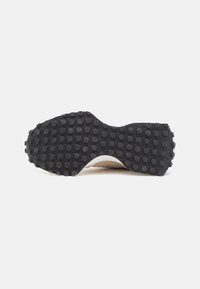 Semelle de chaussure noire avec des crampons circulaires en relief couvrant uniformément toute la surface inférieure, présentée sur un fond blanc uni.
