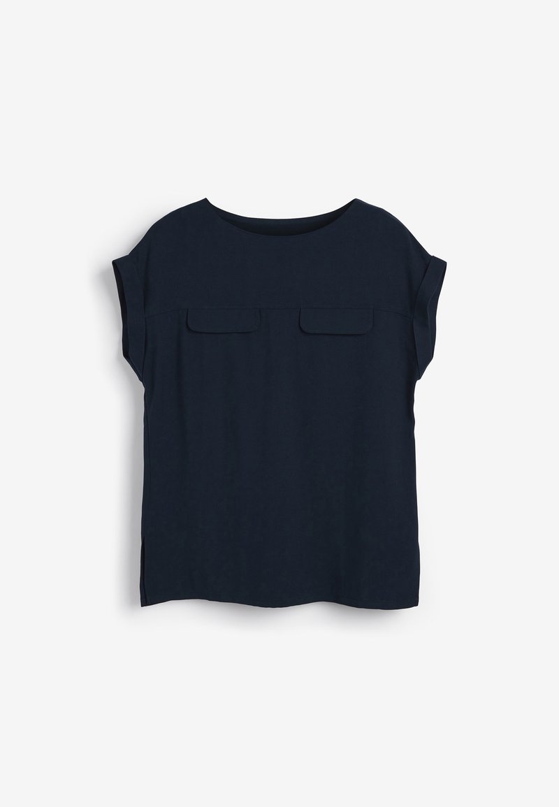 Blouse bleu marine à manches courtes avec encolure arrondie, deux poches à rabat sur la poitrine et petites fentes latérales sur fond blanc.