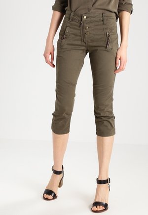 Pantalons courts verts olive avec une coupe slim, fermeture à glissière et bouton, et deux poches avant dotées de fermetures éclair. Tissu lisse et léger.