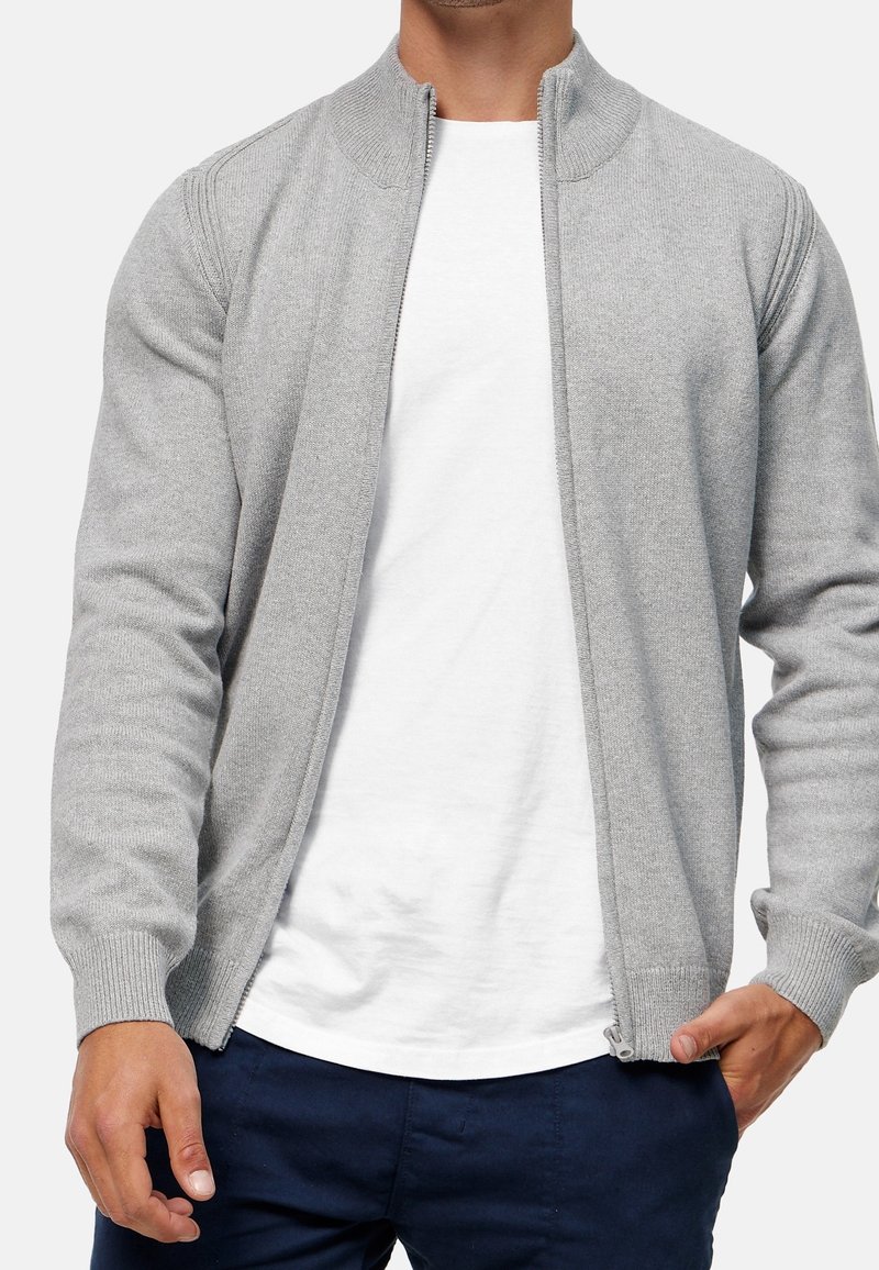 Grå cardigan med lynlås, ribstrikket krave og manchetter. Fremstillet af blødt stof med et rent, strømlinet design og sidelommer.