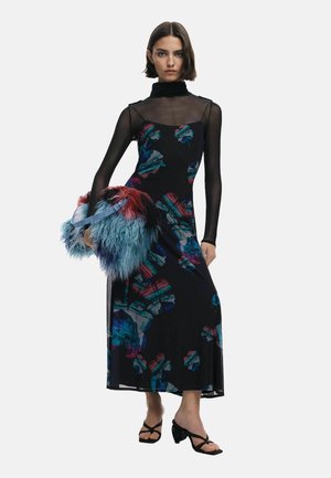 Schwarzes Blumenkleid mit einem durchsichtigen, langärmeligen Rollkragen und bunten Blumenmustern, kombiniert mit einer flauschigen, mehrfarbigen Handtasche.