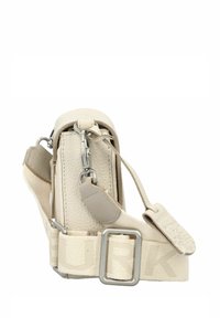 Beige strukturierte Handtasche mit glattem Oberteil, silbernem Zubehör und einem geflochtenen Tragegurt, der das Wort "HURK" in einer helleren Nuance zeigt.