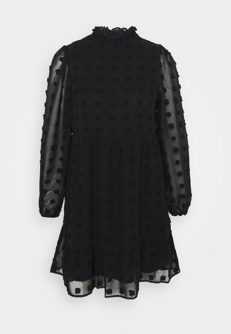 Robe noire avec un col haut à volants, des manches longues en tissu transparent et un tissu texturé avec des pois en relief. Jupe évasée à mi-cuisse.