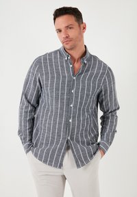 Camisa de botones en azul marino con rayas verticales blancas; cuenta con un cuello, mangas largas y una tela texturizada.