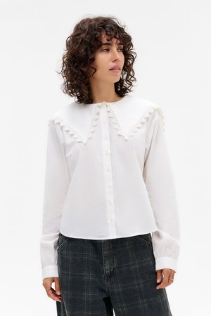 White button-up shirt with a large scalloped collar featuring lace trim, long sleeves with cuffed ends, and a relaxed fit.